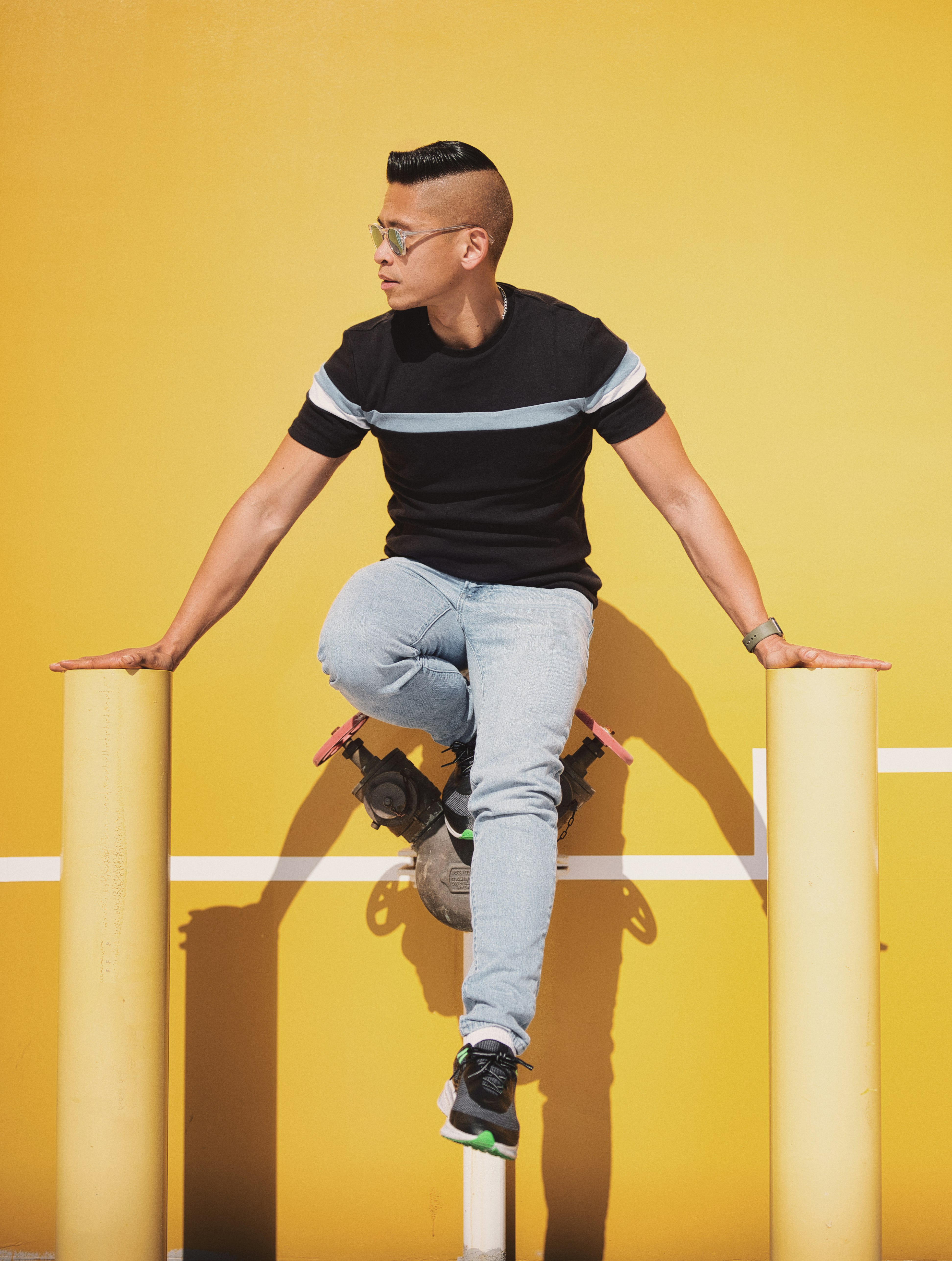 man in black and white crew neck t-shirt and blue denim jeans sitting on yellow